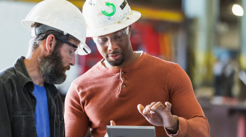 Two men in hardhats looking at a tablet 